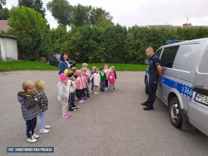 Policjant z przedszkolakami na placu przy Komisariacie Policji w Ożarowie