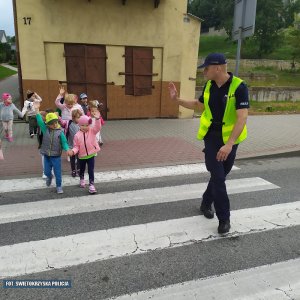 Policjant z dziećmi na przejściu dla pieszych